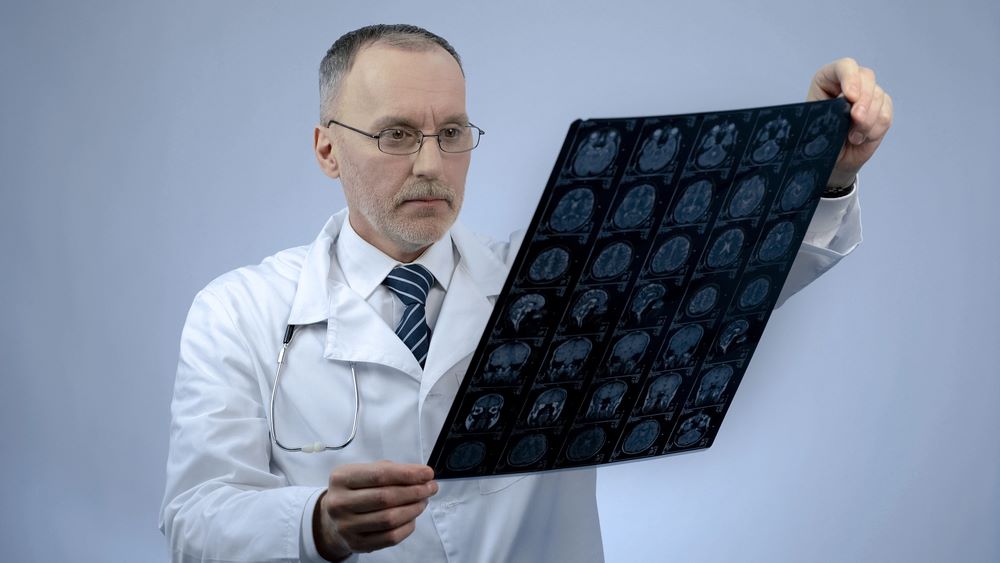 What Is Traumatic Brain Injury (TBI) Image of a professional neurosurgeon checking an MRI brain image, featuring 411 Personal Injury Law, and highlighting the topic 'What Is Traumatic Brain Injury (TBI)?,' ensuring it aligns with the page's context on understanding and treating brain injuries.